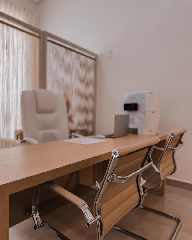 Sala de consulta da clínica, com mesa de madeira e poltronas